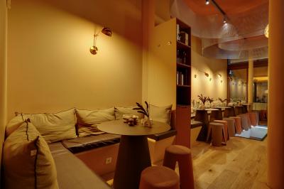 Une personne de dos prépare un cocktail avec un shaker dans un bar, portant un t-shirt blanc à motif orange.