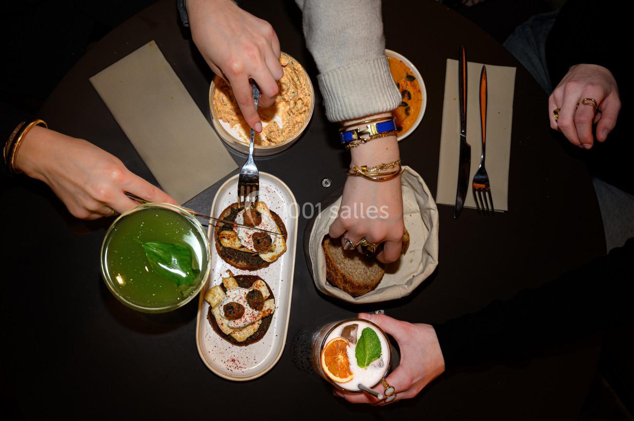 Quatre personnes partageant un repas autour d'une table avec boissons, tartines et plats variés.
