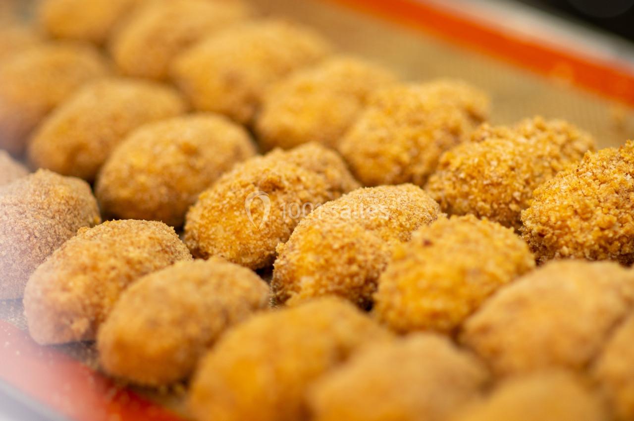 Bouchées panées dorées alignées sur une plaque de cuisson, prêtes à être cuites ou servies.