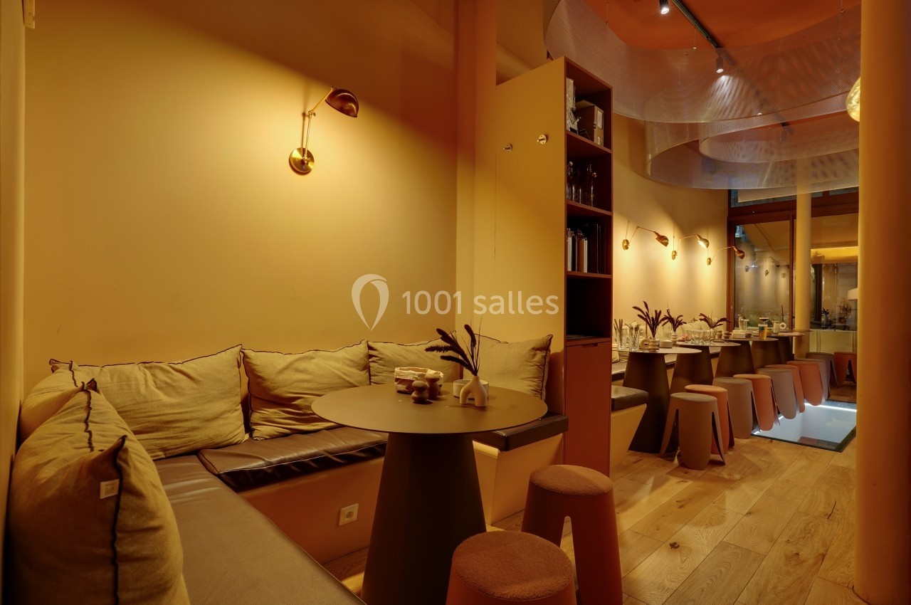 Espace intérieur chaleureux avec banquettes, tables rondes, tabourets et éclairage tamisé.