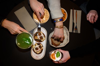 Tartines garnies de fromage frais, cubes de courge rôtie et graines, servies sur une table avec un verre d'eau.