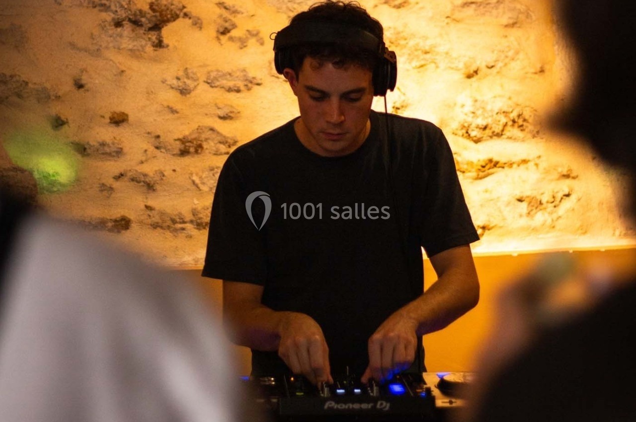 Un DJ mixe de la musique sur une table de mixage dans un environnement à l'éclairage tamisé.