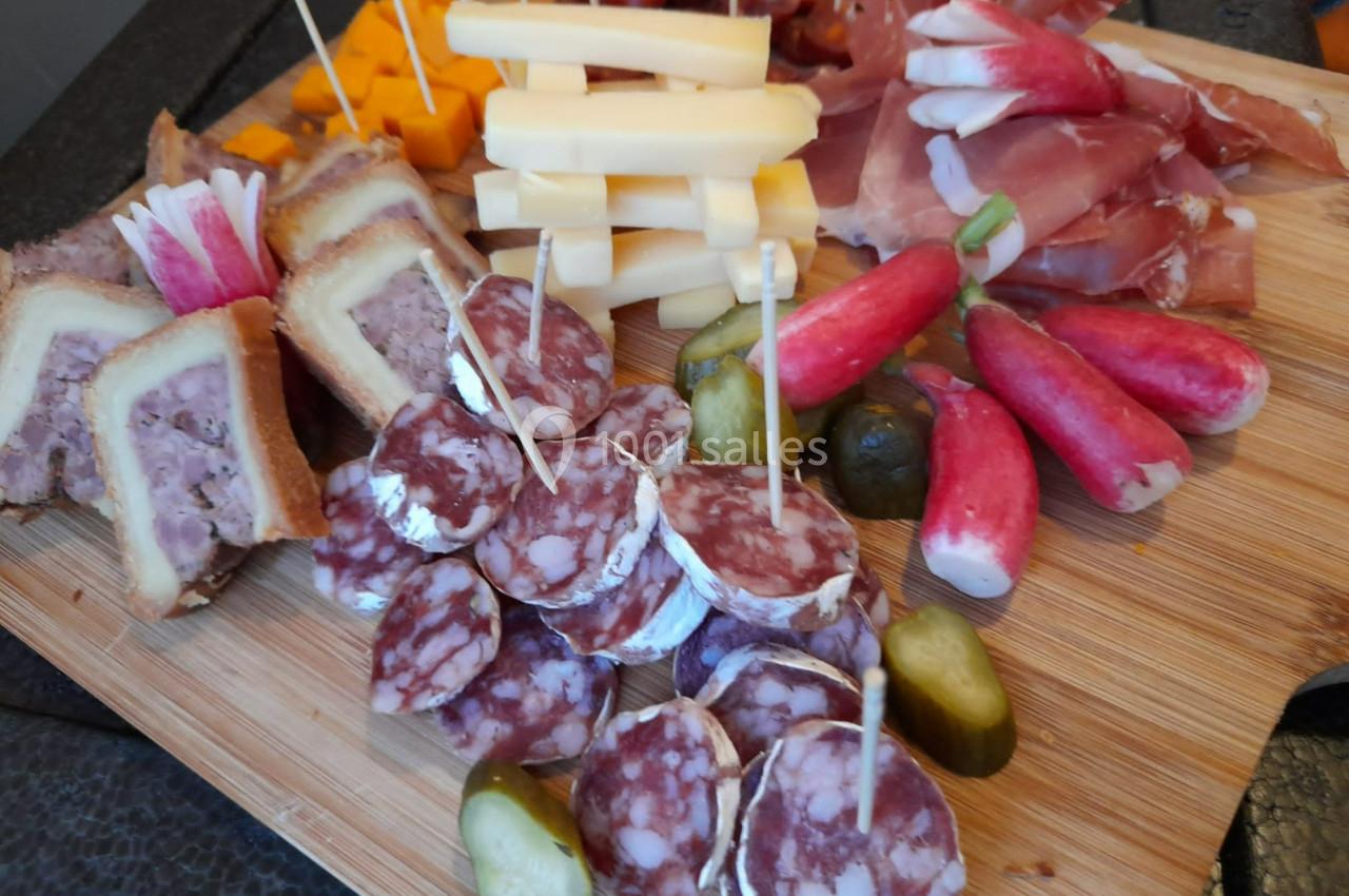Plateau en bois garni de charcuterie, fromages, cornichons, radis et pâté en croûte.