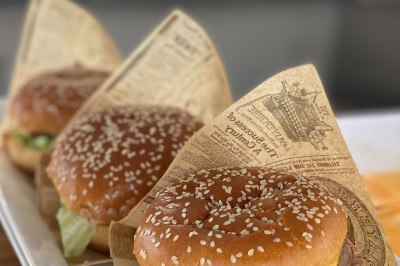 Un food truck bleu avec trois personnes souriantes en tablier devant un comptoir en bois.
