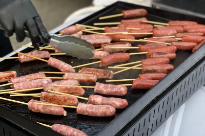 Un food truck bleu avec trois personnes souriantes en tablier devant un comptoir en bois.
