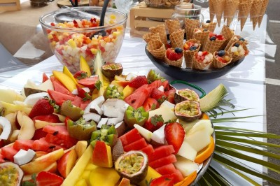 Camion-restaurant bleu vintage devant une concession Mercedes-Benz, avec tables et chaises disposées en terrasse.
