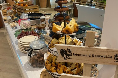 Camion-restaurant bleu vintage devant une concession Mercedes-Benz, avec tables et chaises disposées en terrasse.