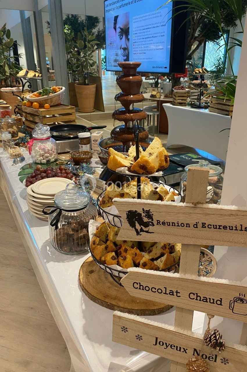 Buffet garni de desserts, fruits, fontaine de chocolat et panneaux décoratifs en bois dans un cadre festif.