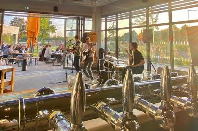 Bar décoré avec des drapeaux internationaux, des bouteilles alignées sur des étagères et des verres suspendus au plafond.
