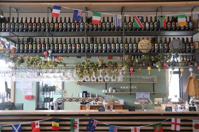 Bar décoré avec des drapeaux internationaux, des bouteilles alignées sur des étagères et des verres suspendus au plafond.