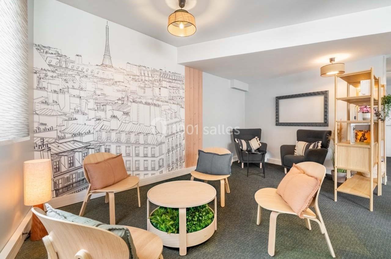 Espace lumineux avec fauteuils, table basse et décoration murale représentant des toits de Paris et la tour Eiffel.