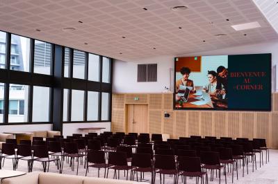 Vue depuis une salle de réunion avec une table, des chaises et une fenêtre donnant sur des immeubles modernes.