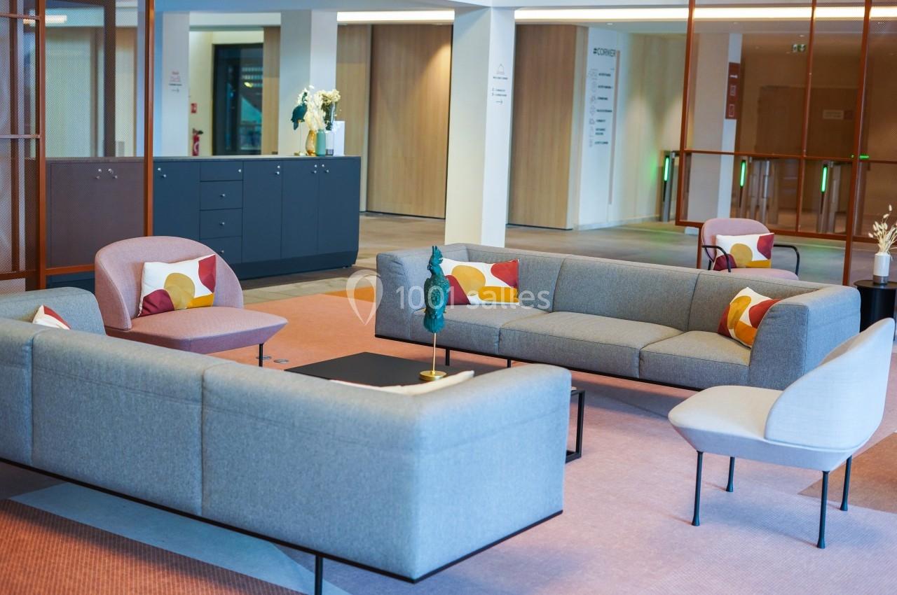 Espace salon moderne avec canapés gris, fauteuils colorés et table basse dans un intérieur lumineux.