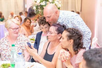 Un magicien réalise un tour de cartes devant des convives assis autour d'une table lors d'un événement festif.