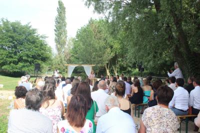 Console de DJ éclairée en violet et jaune, entourée de plantes et d'équipements audio dans une salle sombre.