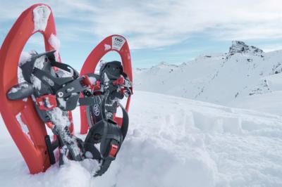 Deux raquettes à neige rouges plantées dans la neige avec des montagnes enneigées en arrière-plan.