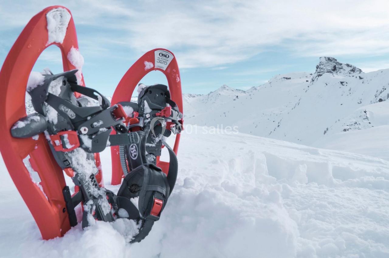 Deux raquettes à neige rouges plantées dans la neige avec des montagnes enneigées en arrière-plan.
