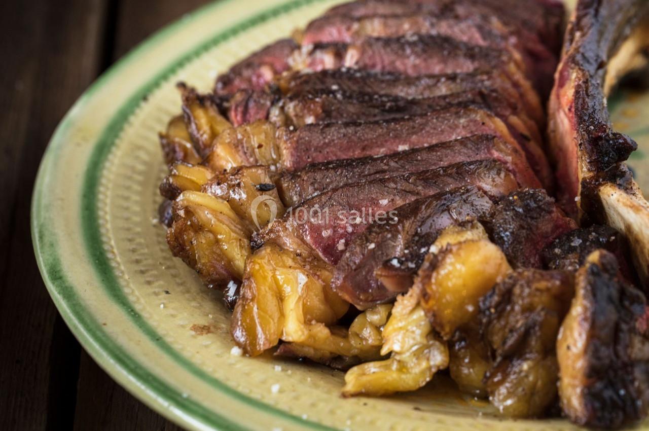Tranche de viande grillée juteuse et marbrée, servie sur une assiette en céramique beige.