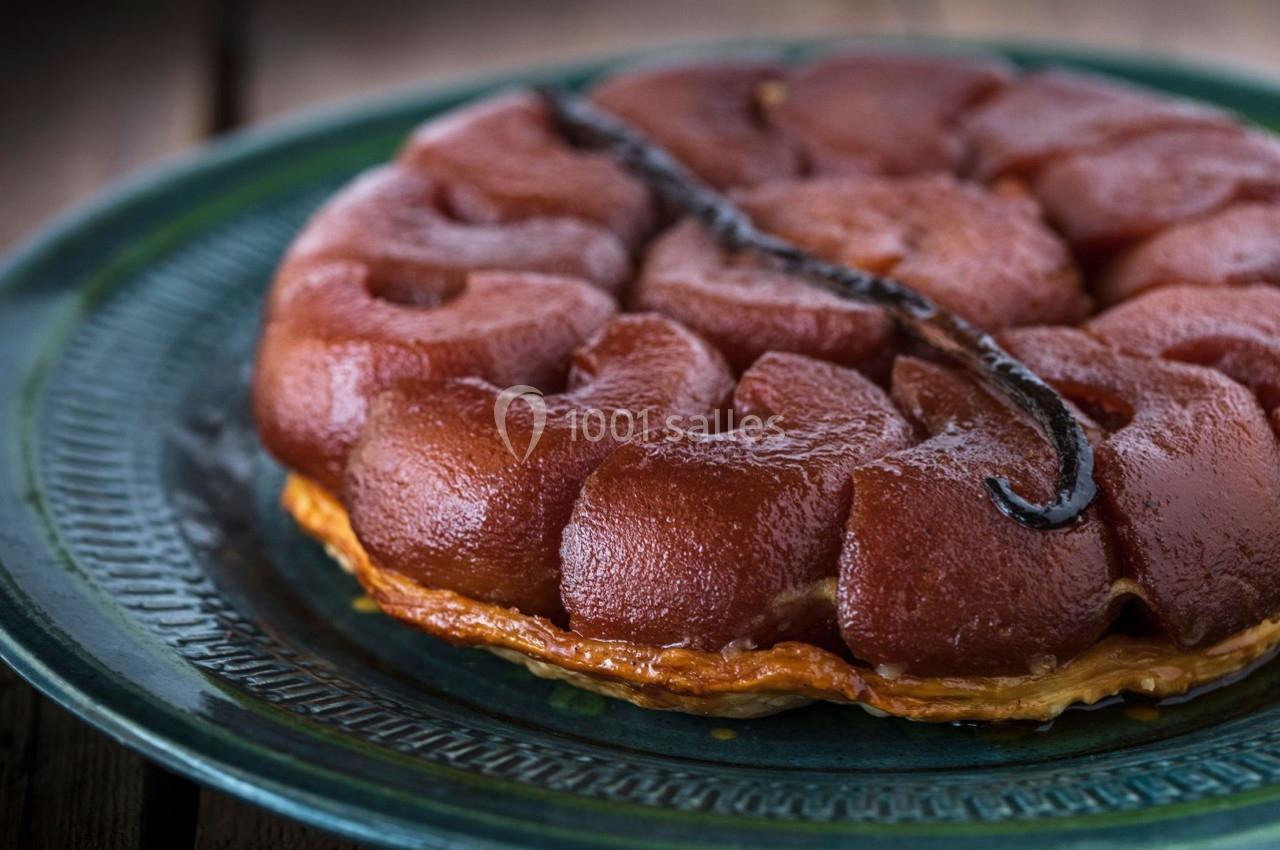 Tarte Tatin caramélisée avec des pommes dorées, servie sur une assiette en céramique verte.
