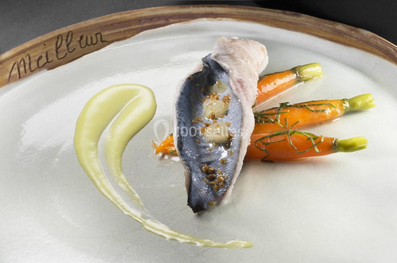 Filet de poisson accompagné de jeunes carottes glacées et d'une purée onctueuse, présenté sur une assiette élégante.