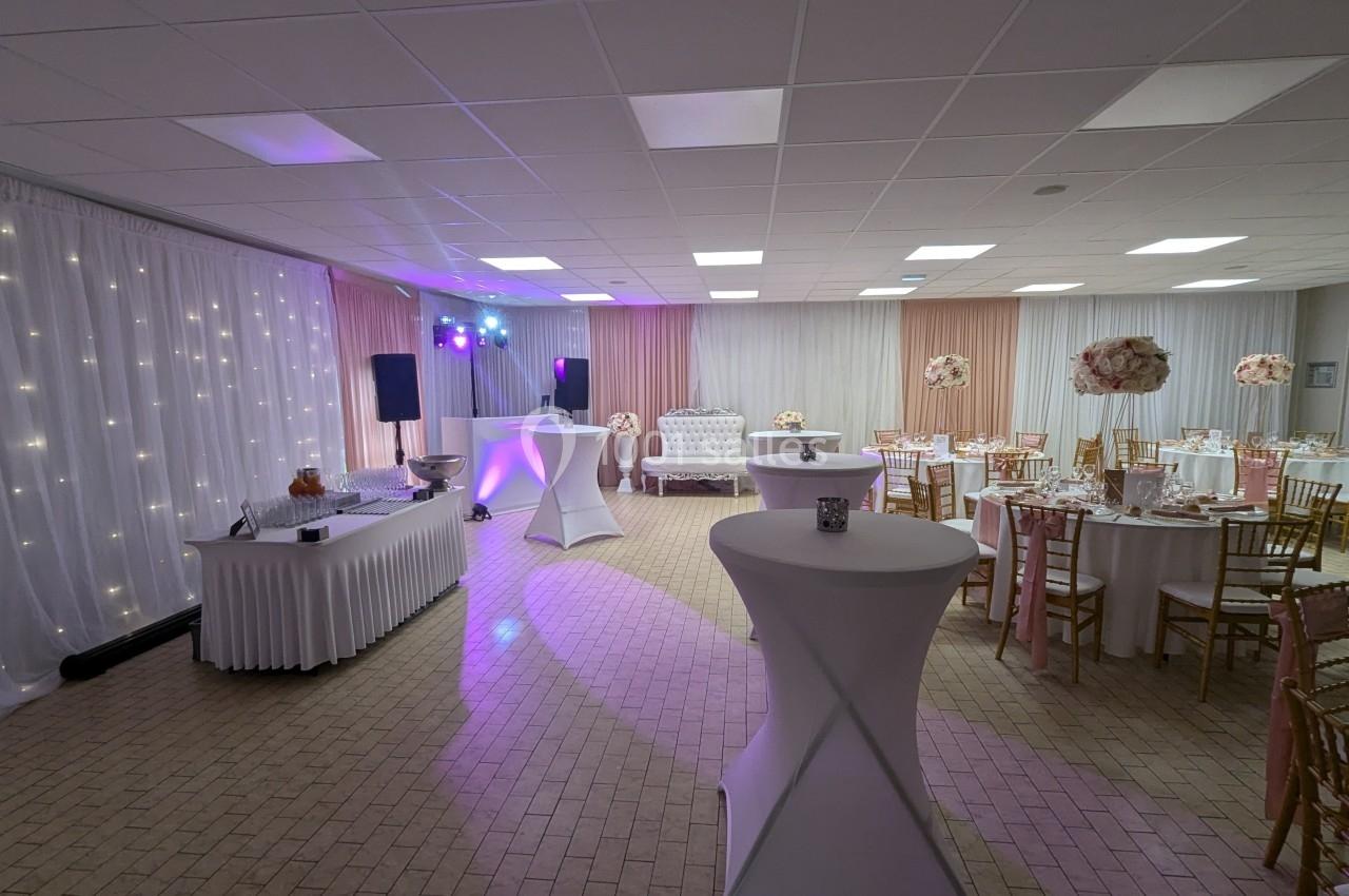 Salle de réception décorée avec des tables rondes, des chaises dorées, un buffet et un éclairage tamisé.