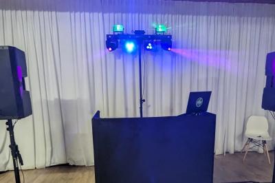 Un homme s'exprime au micro devant un public rassemblé dans une cour extérieure entourée de végétation.