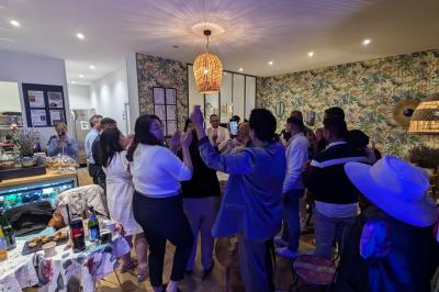 Un homme s'exprime au micro devant un public rassemblé dans une cour extérieure entourée de végétation.