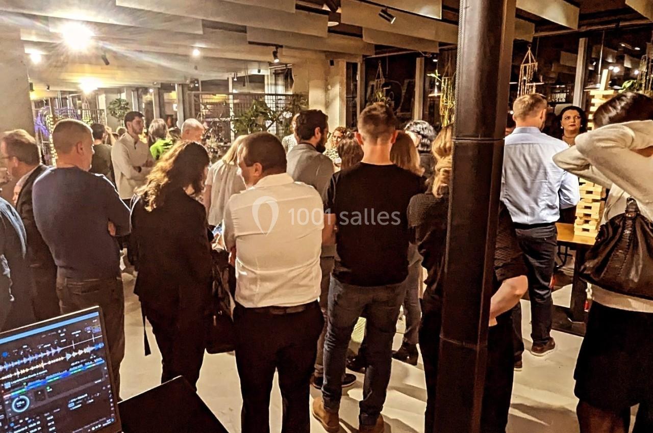 Groupe de personnes rassemblées dans un espace intérieur moderne, avec une table de mixage visible au premier plan.