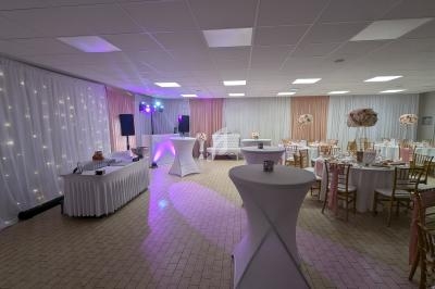 Salle de réception décorée avec des tables rondes, des chaises dorées et un éclairage tamisé.