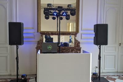 Installation de matériel de sonorisation et d'éclairage dans une salle avec miroir, murs blancs et sol en carreaux rouges.