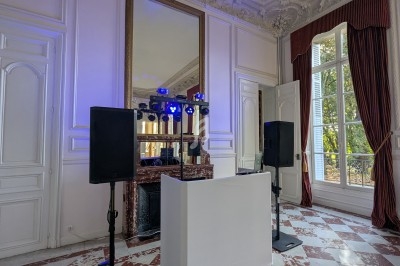 Installation de matériel de sonorisation et d'éclairage dans une salle élégante avec moulures et grandes fenêtres.