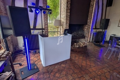 Installation de matériel de sonorisation et d'éclairage dans une salle au style rustique avec cheminée en arrière-plan.