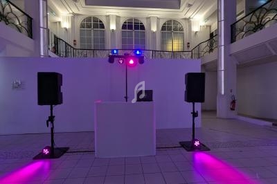 Installation de matériel de sonorisation et éclairage avec une table de mixage dans une salle lumineuse.