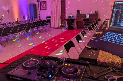 Un homme s'exprime au micro devant un public rassemblé dans une cour extérieure entourée de végétation.