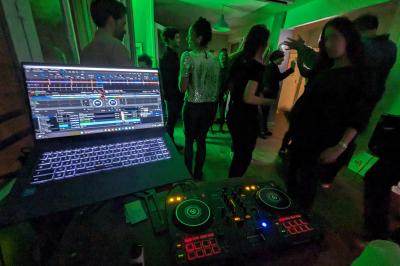 Un homme s'exprime au micro devant un public rassemblé dans une cour extérieure entourée de végétation.