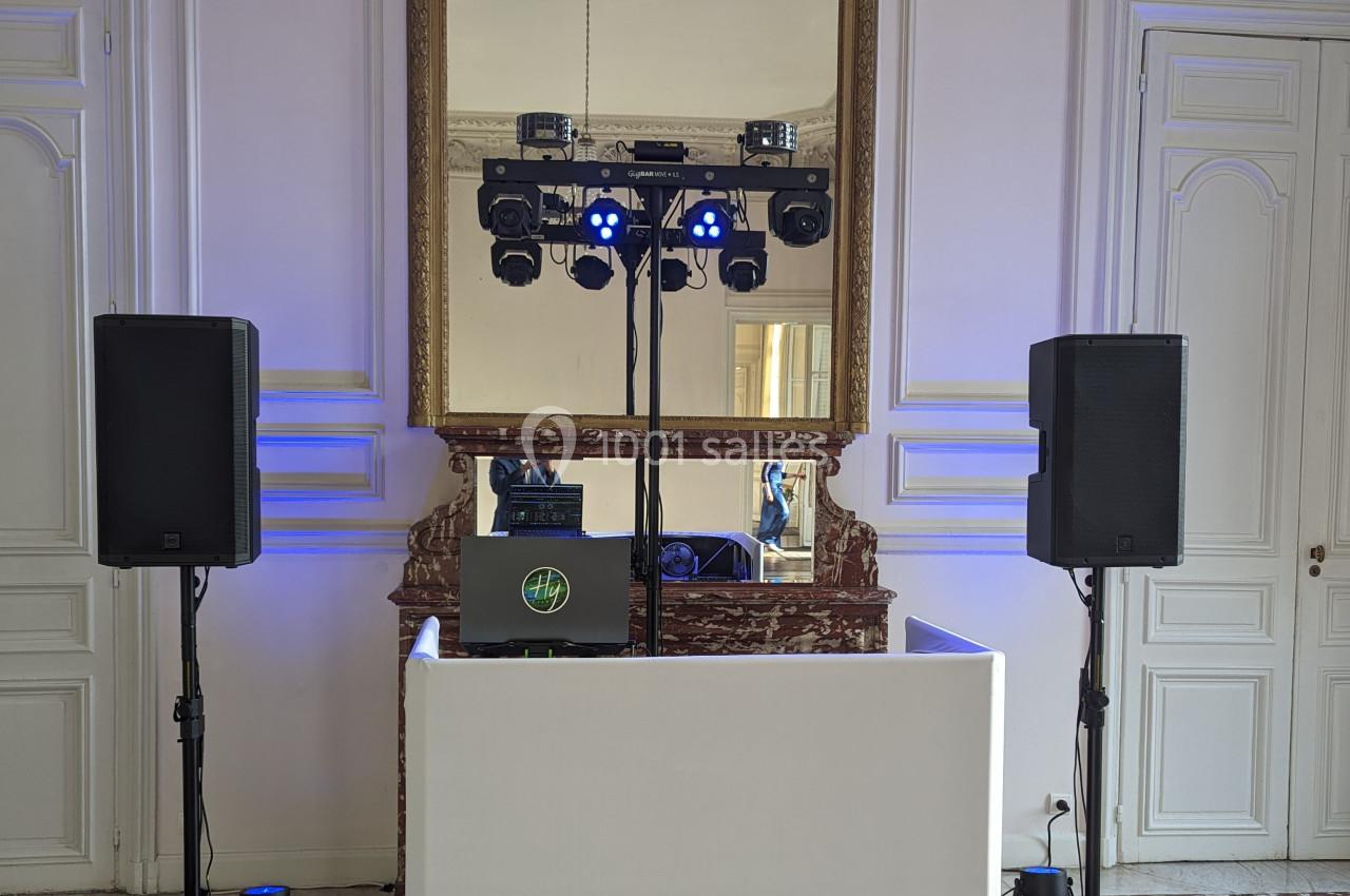 Installation de matériel de sonorisation et d'éclairage dans une salle avec miroir et murs blancs.
