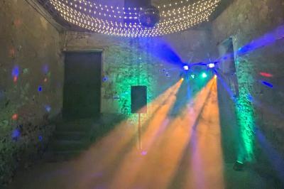 Un homme s'exprime au micro devant un public rassemblé dans une cour extérieure entourée de végétation.