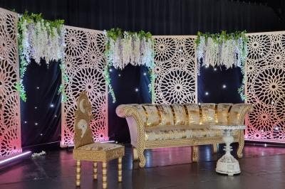Salle de réception décorée avec des tables élégantes, nappes blanches, centres de table lumineux et plumes blanches.