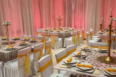 Salle de réception décorée avec des tables élégantes, nappes blanches, centres de table lumineux et plumes blanches.