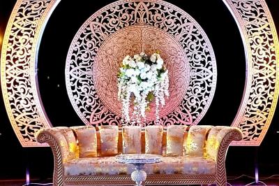 Salle de réception décorée avec des tables élégantes, nappes blanches, centres de table lumineux et plumes blanches.