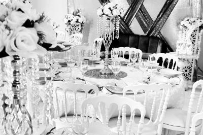 Salle de réception décorée avec des tables élégantes, nappes blanches, centres de table lumineux et plumes blanches.