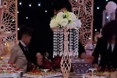 Salle de réception décorée avec des tables élégantes, nappes blanches, centres de table lumineux et plumes blanches.