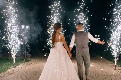 Salle de réception décorée avec des tables élégantes, nappes blanches, centres de table lumineux et plumes blanches.