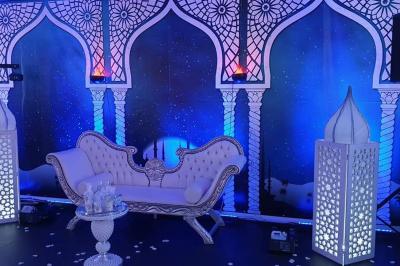 Salle de réception décorée avec des tables élégantes, nappes blanches, centres de table lumineux et plumes blanches.