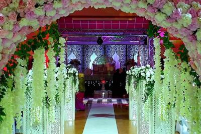 Salle de réception décorée avec des tables élégantes, nappes blanches, centres de table lumineux et plumes blanches.