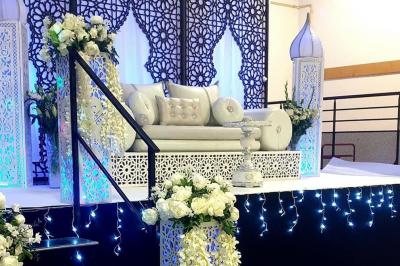 Salle de réception décorée avec des tables élégantes, nappes blanches, centres de table lumineux et plumes blanches.