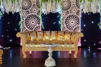 Salle de réception décorée avec des tables élégantes, nappes blanches, centres de table lumineux et plumes blanches.