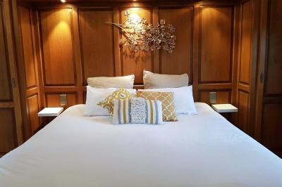 Chambre avec lit double, baignoire îlot, parquet, carrelage hexagonal et échelle porte-serviettes.