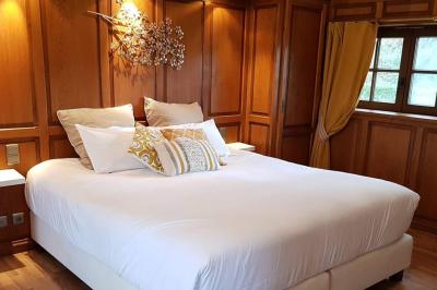 Chambre avec lit double, baignoire îlot, parquet, carrelage hexagonal et échelle porte-serviettes.