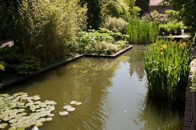 Chambre avec lit double, baignoire îlot, parquet, carrelage hexagonal et échelle porte-serviettes.